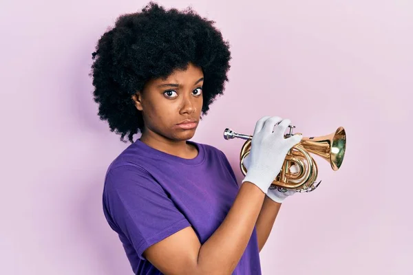 若いアフリカ系アメリカ人女性がトランペットを吹いて懐疑的で緊張し 問題のために動揺を眉をひそめています 否定的な人 — ストック写真
