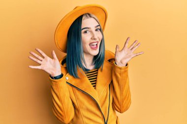 Sarı şapkalı ve deri ceketli genç bir kız çılgın ve başarıyı kollarını kaldırıp heyecanla haykırarak kutluyor. Kazanan konsept 