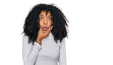 Gündelik giysiler giyen genç Afro-Amerikan kızı elleri çenesinde olan inançsızlıktan, şaşkınlıktan ve şaşkınlıktan büyülenmiş görünüyor. 