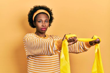 Genç Afro-Amerikalı kadın spor giyer ve kol bandı takar yüzünde ciddi bir ifadeyle rahatlar. Basit ve doğal bir şekilde kameraya bakıyorsun.. 