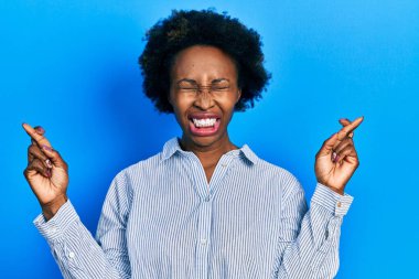 Genç Afro-Amerikan kadın günlük kıyafetler giyip umut ve gözlerin kapalı bir şekilde gülümseyerek el işareti yapıyor. Şans ve batıl inançlar. 