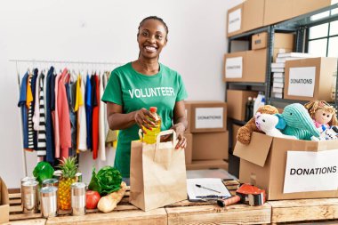 Genç Afro-Amerikalı gönüllü kadın yardım merkezinde içi yiyecek dolu kağıt torba hazırlıyor..