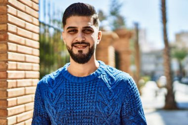 Sokakta kendinden emin gülümseyen genç bir Arap.