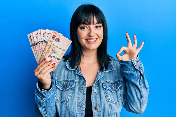 Young Hispanic Woman Holding Saudi Arabia Riyal Banknotes Doing Sign — Fotografia de Stock