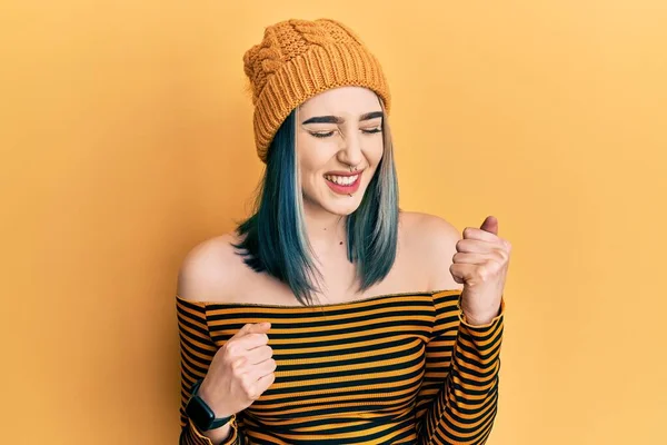 Başarı için heyecanlanan yün şapkalı genç bir kız kolları havada ve gözleri kapalı zaferi kutlarken gülümsüyor. Kazanan konsept. 