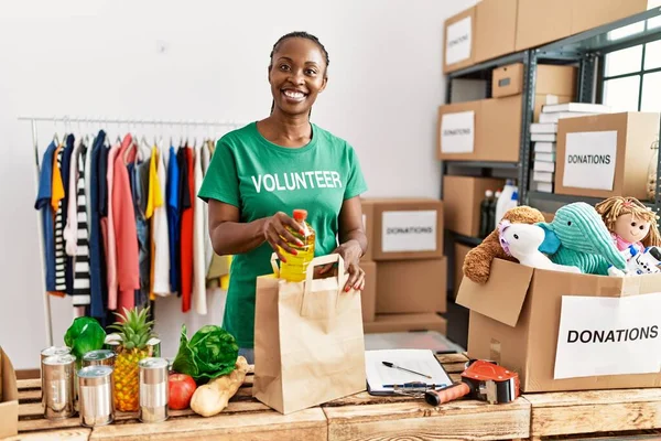 Genç Afro-Amerikalı gönüllü kadın yardım merkezinde içi yiyecek dolu kağıt torba hazırlıyor..