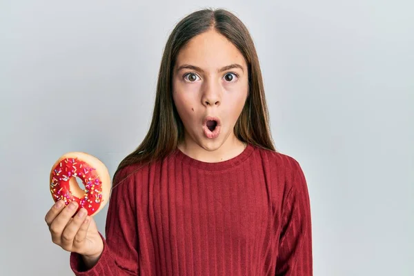 Beautiful Brunette Little Girl Holding Tasty Colorful Doughnut Scared Amazed — Zdjęcie stockowe