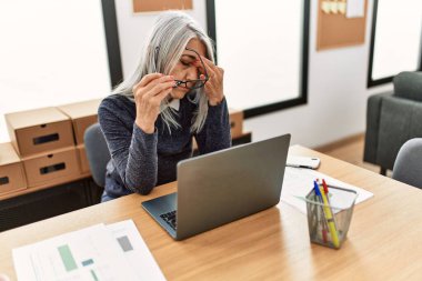 Orta yaşlı, kır saçlı, iş kadını. Ofiste baş ağrısı çekiyor.