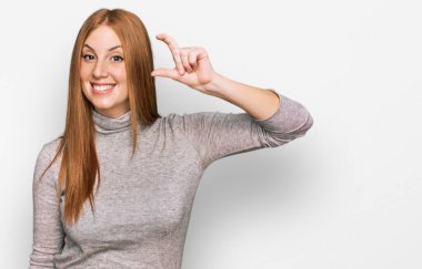 Genç İrlandalı kadın günlük kıyafetler giyiyor gülümsüyor ve el hareketleriyle küçük boy işaretler yapıyor parmaklarıyla bakıyor ve kameraya bakıyor. ölçüm kavramı. 