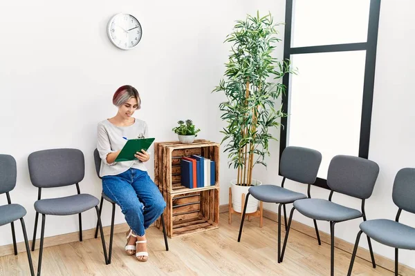 Young Caucasian Girl Smiling Happy Writing Clipboard Waiting Room — стоковое фото