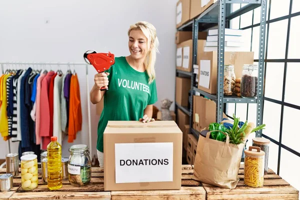 Genç sarışın gönüllü kız gülümsüyor. Yardım merkezinde çalışmaktan mutlu..