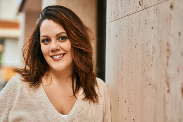 Genç İrlandalı artı cüsseli kız gülümseyerek şehirde mutlu mesut duruyor..