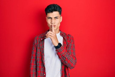 Gündelik kıyafetler giyen genç İspanyol adam parmakları dudaklarında sessiz olmak istiyor. sessizlik ve gizli konsept. 