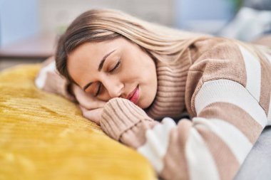 Young woman lying on sofa sleeping at home clipart