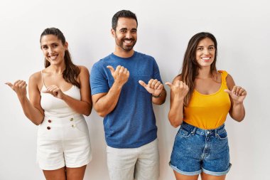 Bir grup İspanyol genç, izole edilmiş arka planda durup elleri ve başparmakları havada, kendinden emin gülümseyen insanları işaret ediyor. 