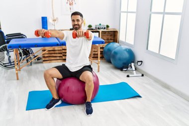 Genç İspanyol hasta, rehabilitasyon seansında sağlıklı top ve dambıllarla gülümsüyor.