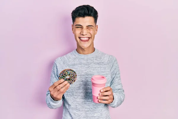 Jovem Hispânico Comendo Donut Bebendo Café Piscando Olhando Para Câmera — Fotografia de Stock