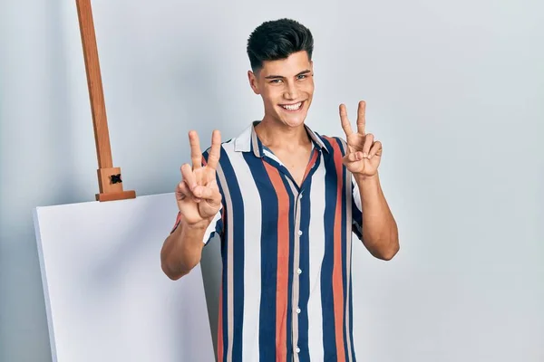 Young Hispanic Man Standing Close Empty Canvas Smiling Looking Camera — 스톡 사진