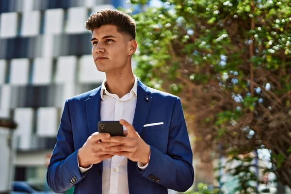 Genç adam parkta akıllı telefon kullanıyor.