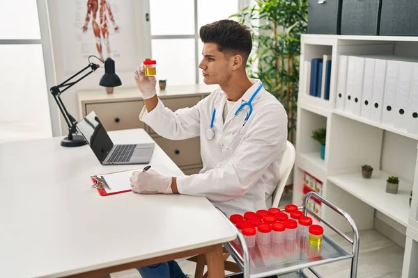 Young Hispanic Man Wearing Doctor Uniform Analysing Urine Test Tube — ストック写真