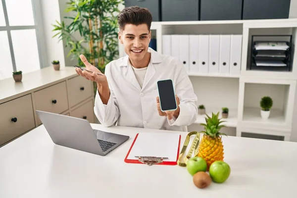 Junger Hispanischer Mann Ernährungsberater Uniform Zeigt Bildschirm Smartphone Klinik — Stockfoto