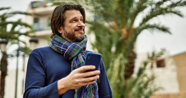 Parkta akıllı telefon kullanan orta yaşlı yakışıklı bir adam.