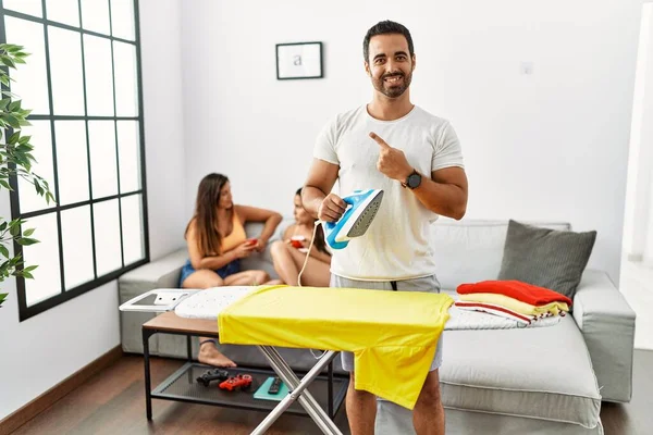 Young Hispanic Man Ironing Clothes Home Cheerful Smile Face Pointing — Stockfoto