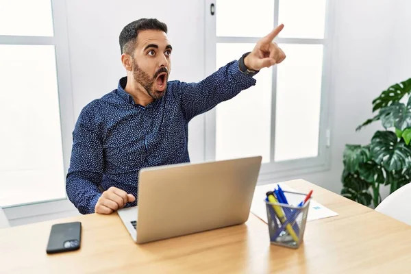 Young Hispanic Man Beard Working Office Laptop Pointing Finger Surprised — ストック写真