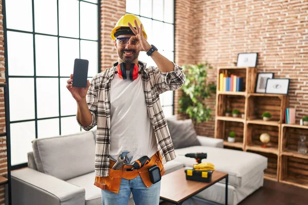 Young Hispanic Man Beard Working Home Renovation Holding Smartphone Smiling — стоковое фото