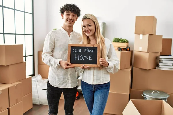 Genç ve güzel bir çift gülümsüyor. İlk ev mesajımızla birlikte ellerinde tahta tutuyorlar..