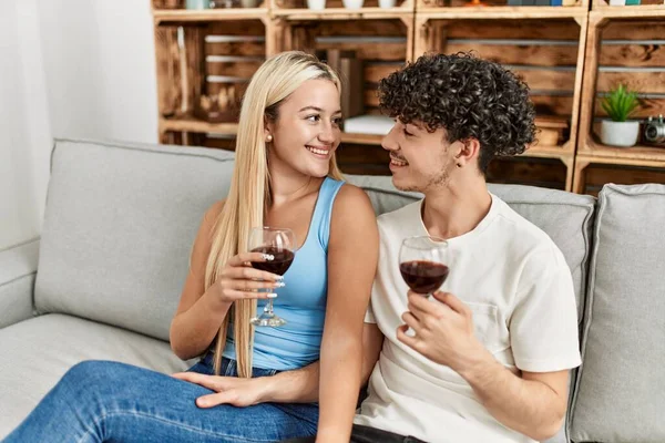 Genç çift mutlu bir şekilde kadeh kaldırıyor kırmızı şarap kadehiyle evde..