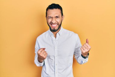 Sakallı, iş gömleği giyen, kolları havada, gözleri kapalı zaferi kutlayan İspanyol bir adam. Kazanan konsept. 