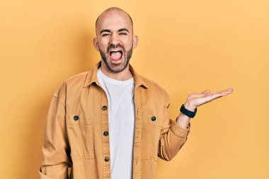 Genç kel adam avuçlarını açmış, elinde bir şeyle gülüyor ve kahkahalarla gülüyor.. 