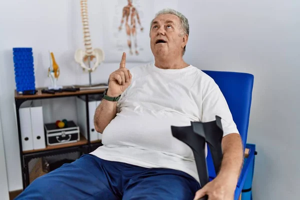 Hombre Caucásico Mayor Clínica Fisioterapia Sosteniendo Muletas Asombrado Sorprendido Mirando —  Fotos de Stock