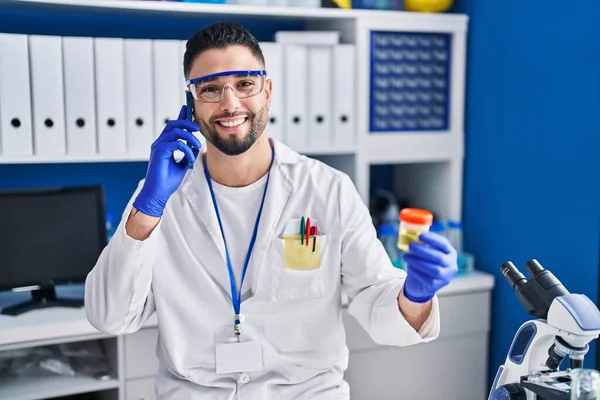 Young Arab Man Scientist Talking Smartphone Holding Urine Test Tube — стоковое фото