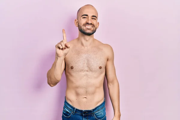 Young Bald Man Standing Shirtless Showing Pointing Finger Number One — Stockfoto