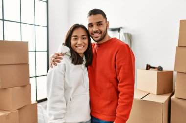 Genç Latin çift gülümsüyor mutlu bir şekilde yeni evinde duruyor.