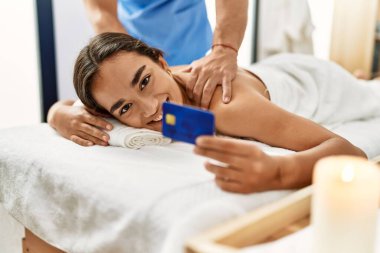 Latin erkek ve kadın fizyoterapi üniforması giyip güzellik merkezinde sırt masajı yapıyorlar.