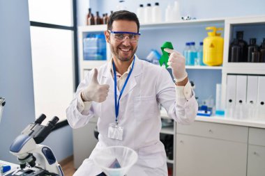 Sakallı, sakallı, elinde yeşil kurdele tutan, mutlu ve pozitif gülümseyen bir bilim adamı. 