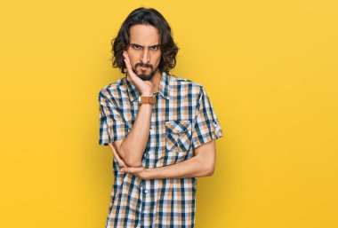 Günlük kıyafetler giyen genç İspanyol adam kollarını kavuşturarak depresyondan sıkılmış ve yorgun görünüyor.. 