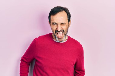 Orta yaşlı İspanyol bir adam, sıradan kıyafetler giymiş, kameraya seksi bir ifadeyle bakıyor, neşeli ve mutlu bir yüzle.. 