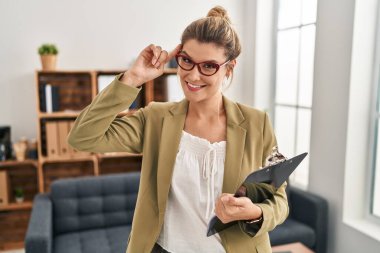 Young woman working at consultation office smiling pointing to head with one finger, great idea or thought, good memory 