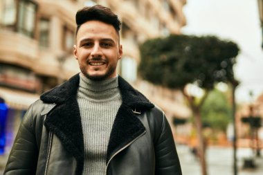 Genç Arap adam gülümsüyor, mutlu bir şekilde şehirde duruyor..