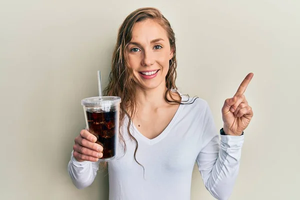 Young Blonde Woman Drinking Glass Soda Beverage Smiling Happy Pointing — Stock fotografie