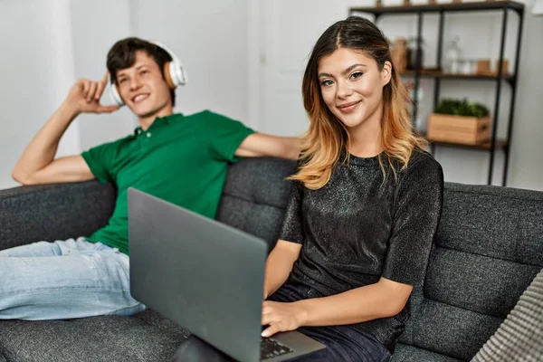 年轻的高加索夫妇在家里用笔记本电脑和耳机开心地笑着 — 图库照片