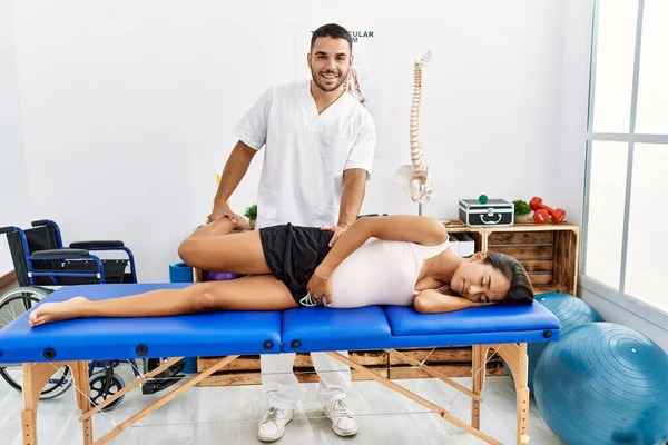 在理疗诊所穿着理疗制服的拉丁男性和女性在怀孕康复期间伸展腿 — 图库照片