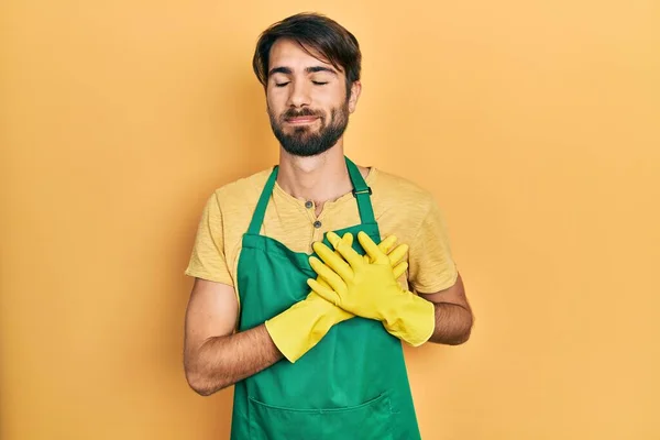 Young Hispanic Man Wearing Cleaner Apron Gloves Smiling Hands Chest — Foto de Stock
