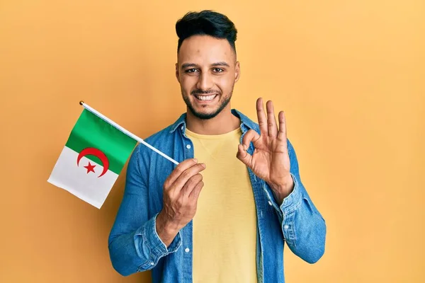 Young Arab Man Holding Algeria Flag Doing Sign Fingers Smiling — Stockfoto