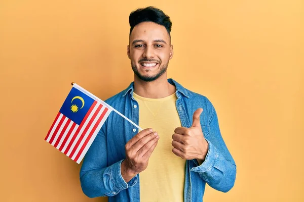 Young Arab Man Holding Malaysia Flag Smiling Happy Positive Thumb — 스톡 사진