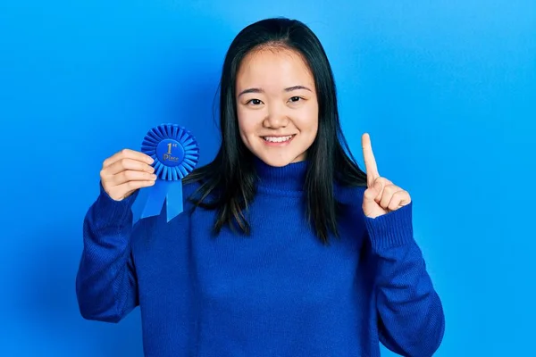 Young Chinese Girl Holding First Place Badge Smiling Idea Question — Stock Fotó